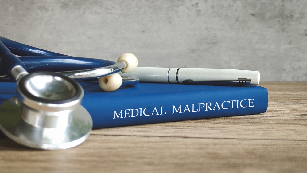 stethoscope,and,a,pen,on,a,book,titled,"medical,malpractice,"